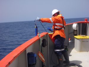 man deploying water logger over the side of a boat